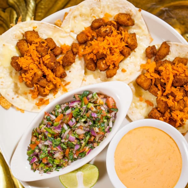 Three Don Pedro Mexican Restaurant tacos with fried chicken, shredded cheese, salsa, and sauce.